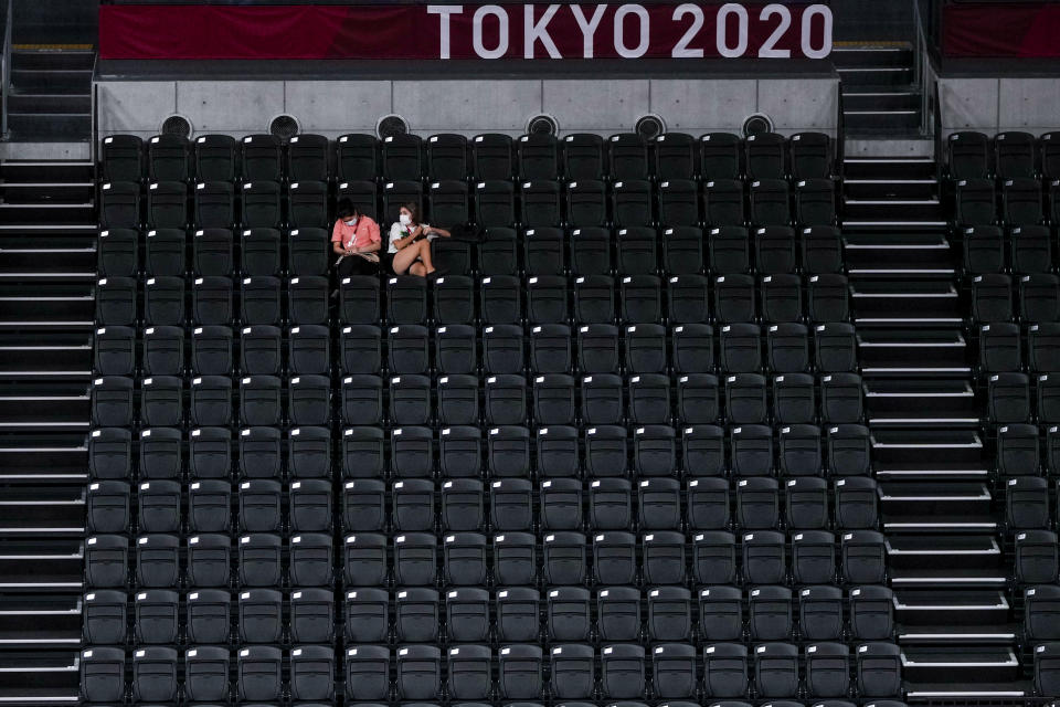 People sit in an empty tribune during a volleyball team training session at Ariake Arena at the 2020 Summer Olympics, Thursday, July 22, 2021, in Tokyo, Japan. (AP Photo/Manu Fernandez)