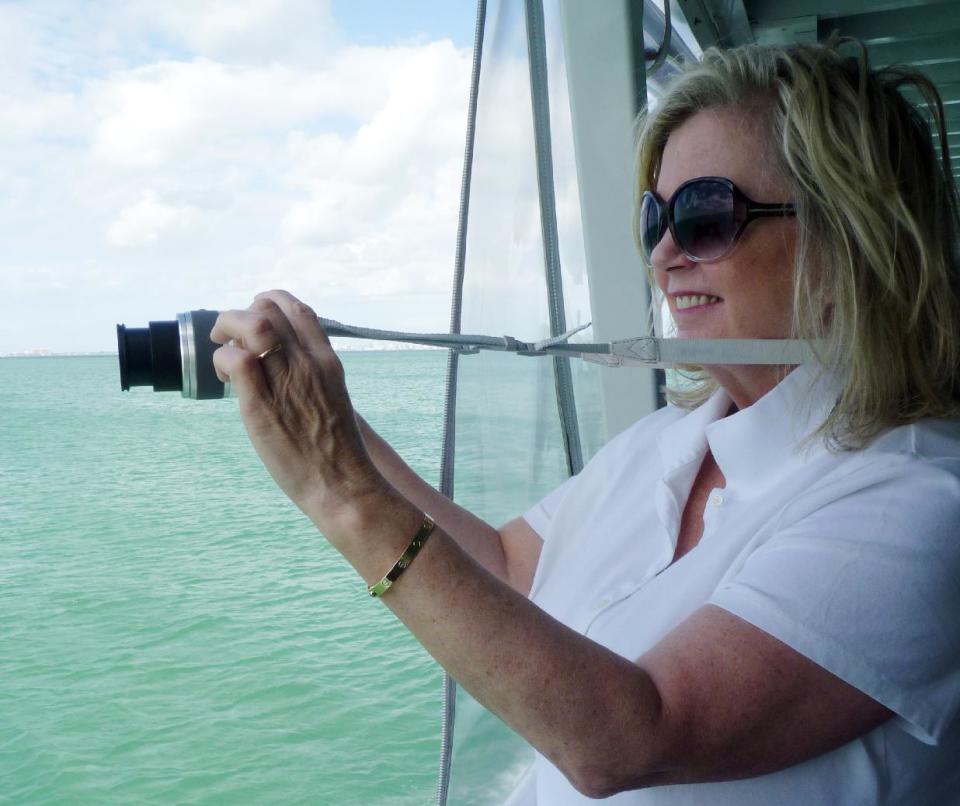 In this photo taken Sunday, Nov. 11, 2012, Karen Clark of Saratoga Springs, N.Y., takes a photo of one of the seven Stiltsville homes near Miami, Fla. The narrated tour tells the colorful story of these homes perched above the shallow waters of Biscayne Bay. (AP Photo/Suzette Laboy)
