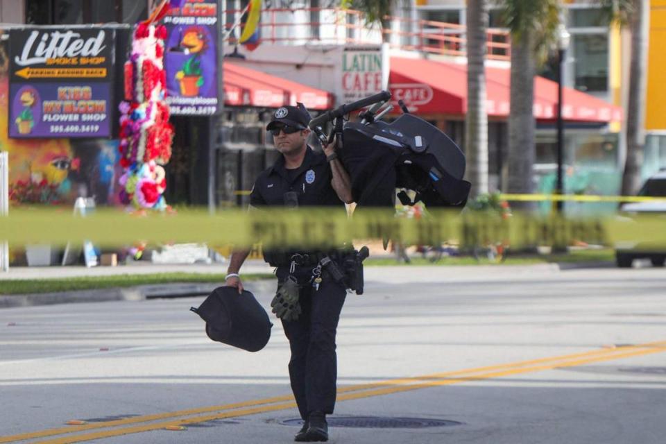 A Miami police officer carries a stroller on Biscayne Boulevard on Wednesday, Feb. 14, 2024, after a woman pushing a baby was killed in a crash hours earlier.