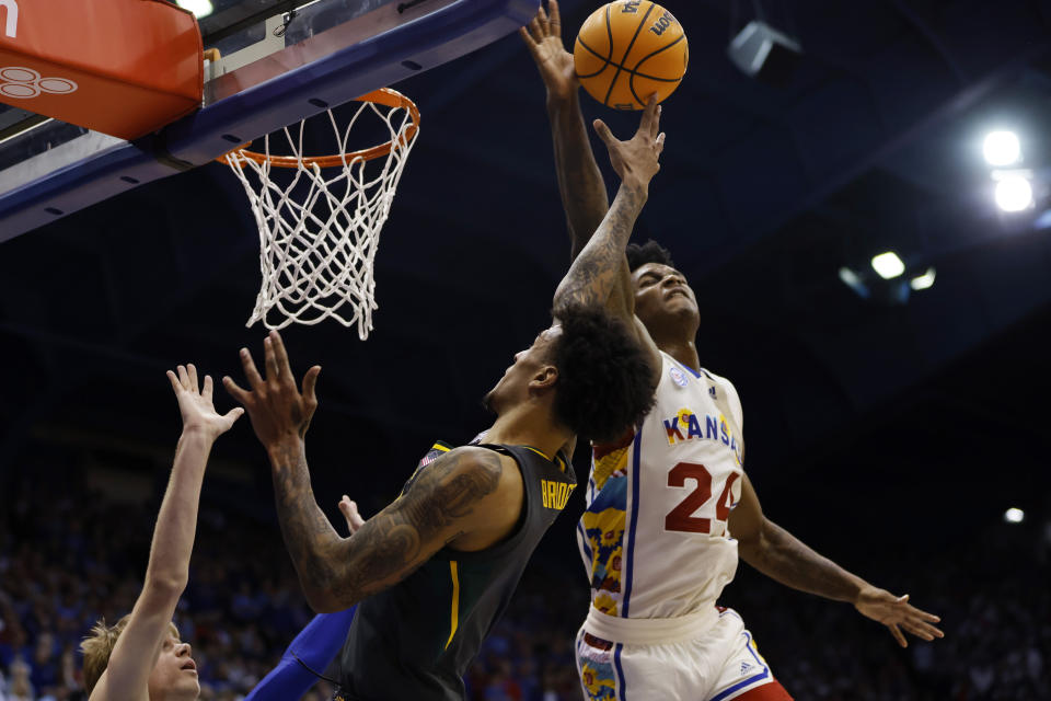 Kansas forward K.J. Adams Jr. (24) blocks a shot by Baylor forward Jalen Bridges, center, as Kansas guard Gradey Dick, left, also defends during the second half of an NCAA college basketball game, Saturday, Feb. 18, 2023, in Lawrence, Kan. (AP Photo/Colin E. Braley)