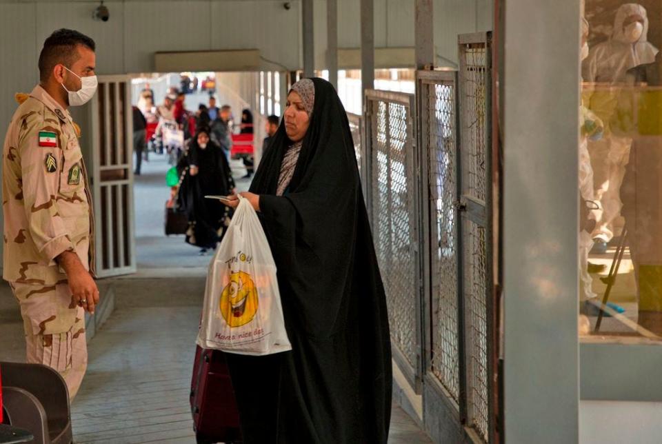 An Iraqi traveler shows her passport to an Iranian officer at the Shalamjah border crossing, some 15 kilometers southeast of the city of Basra, upon their return from Iran on Feb. 21, 2020. Iran reported two more deaths among 13 new cases of coronavirus in the Islamic republic, bringing the total number of deaths to four and infections to 18. Following the announcement, Iraq clamped down on travel to and from the Islamic republic. The health ministry in Baghdad said people from Iran had been barred from entering Iraq "until further notice".