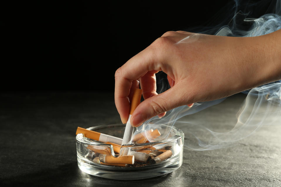 Smoking. Woman extinguishing cigarette in glass ashtray