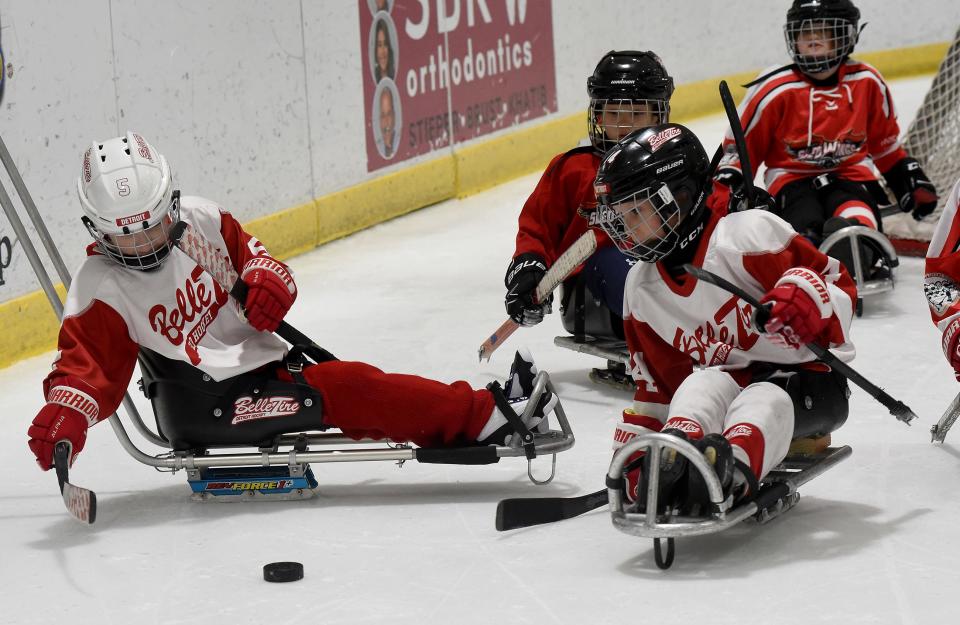 Conner Adcock, 9, (left) of Flat Rock attempts to get to the puck to hit with his Belle Tire Sled Hockey teammate as they played in the Motown sled hockey tournament at Taylor Sportplex Jan. 20, 2024.