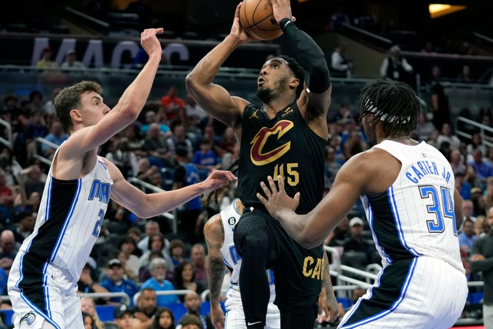 Cavaliers guard Donovan Mitchell scores between Magic defenders Franz Wagner, left, and Wendell Carter Jr. (34) during the first half, Tuesday, April 4, 2023, in Orlando.