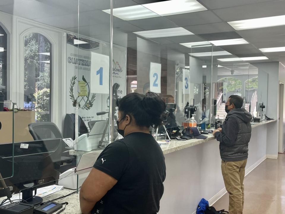 Two people standing at a counter in a consulate office