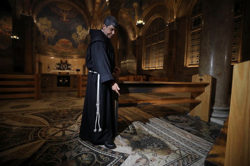 A priest inspects a damaged church floor after a man tried to set fire to the Church of All Nations next to the Garden of Gethsemane in Jerusalem