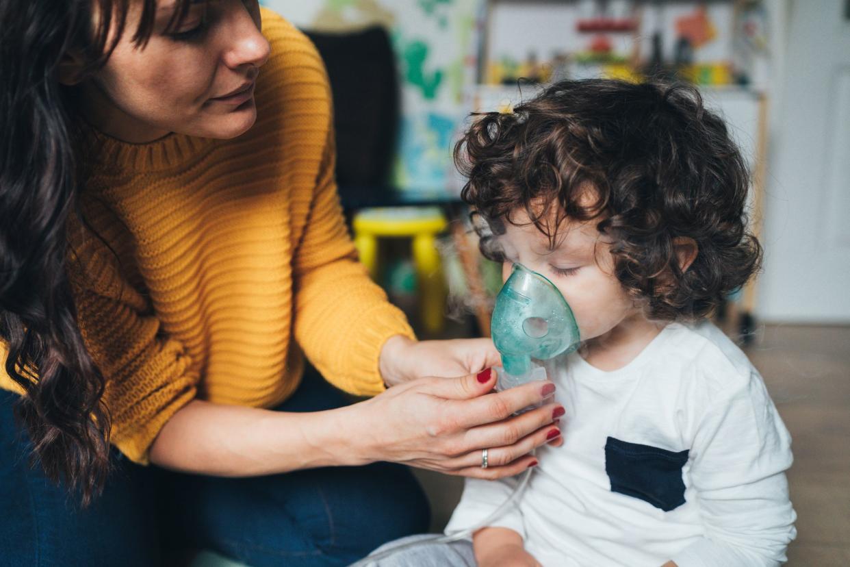 Mother helps her little boy to makes inhalation at home