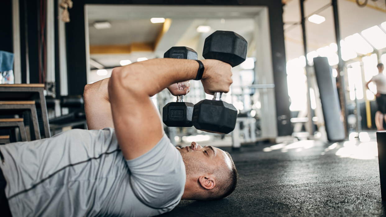  Man doing floor-based skullcrushers. 