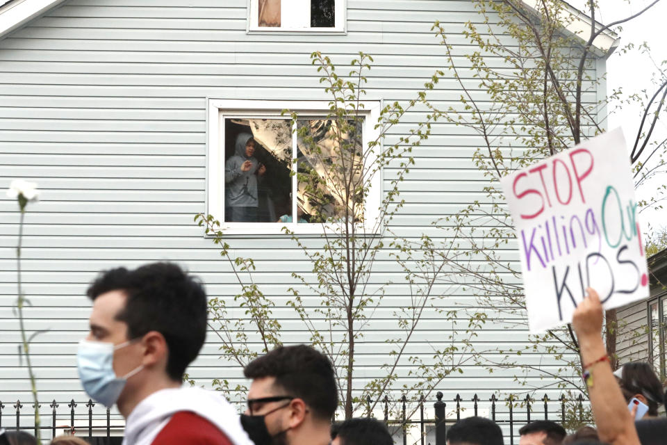A kid looks out of a window as demonstrators attend a peace walk honoring the life of police shooting victim 13-year-old Adam Toledo, Sunday, April 18, 2021, in Chicago's Little Village neighborhood. (AP Photo/Shafkat Anowar)