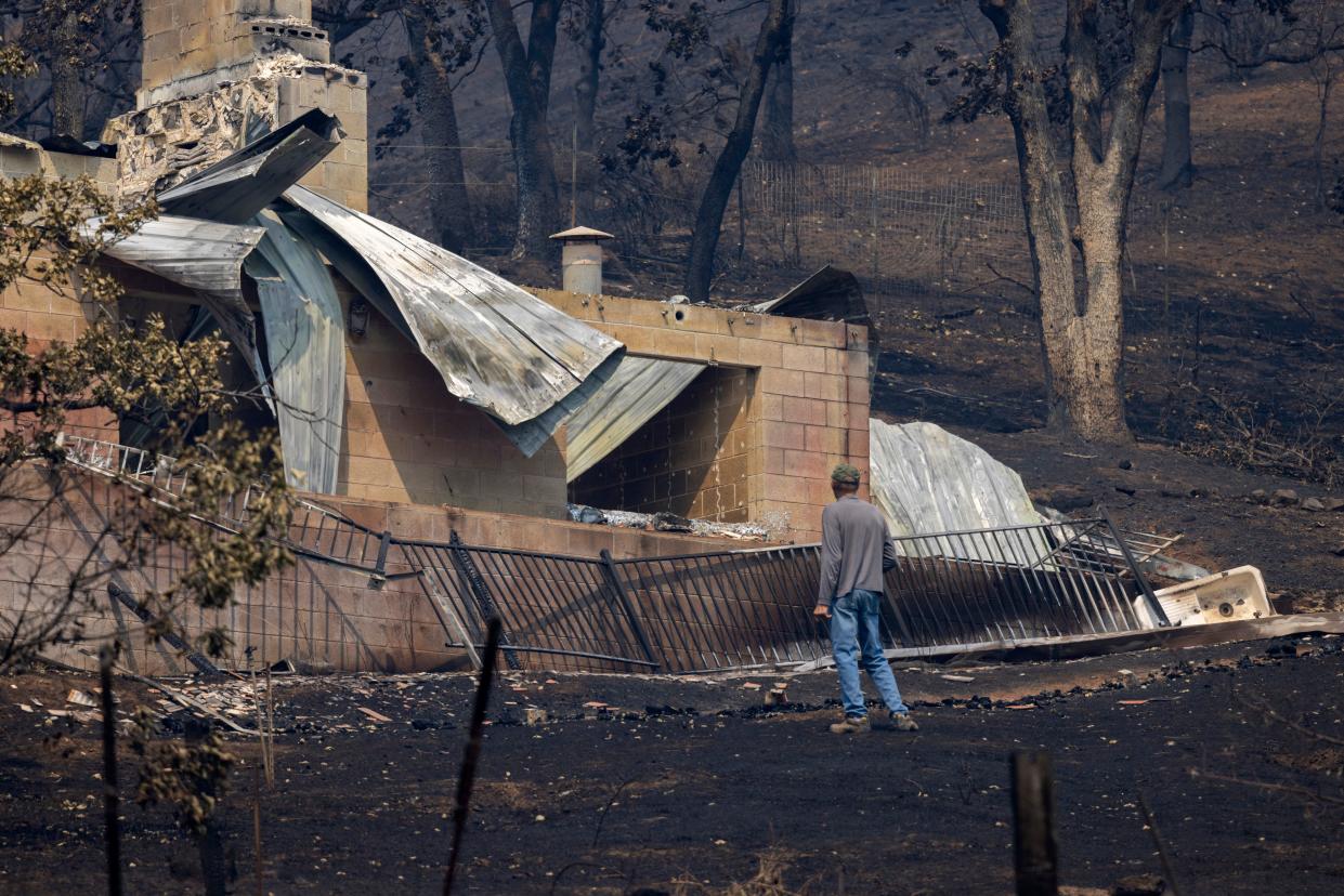 A man looks around property where a house was destroyed by the McKinney Fire.