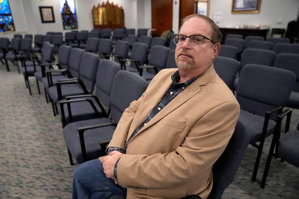 In this Dec. 22, 2022, photo, Jeff Cohen poses for a photo in the area of Congregation Beth Israel where he was sitting when taken hostage in Colleyville, Texas. The violence left the synagogue with broken doors, shattered glass and bullet holes. Within three months, repairs had been made and the congregation returned.