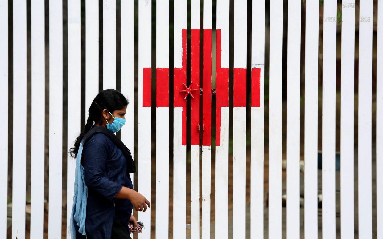 An Indian walks in front of the 'Red Cross' symbol painted on a fence during an extended lockdown over suspected coronavirus disease (COVID-19) cases in Bangalore, India - JAGADEESH NV/EPA-EFE/Shutterstock 