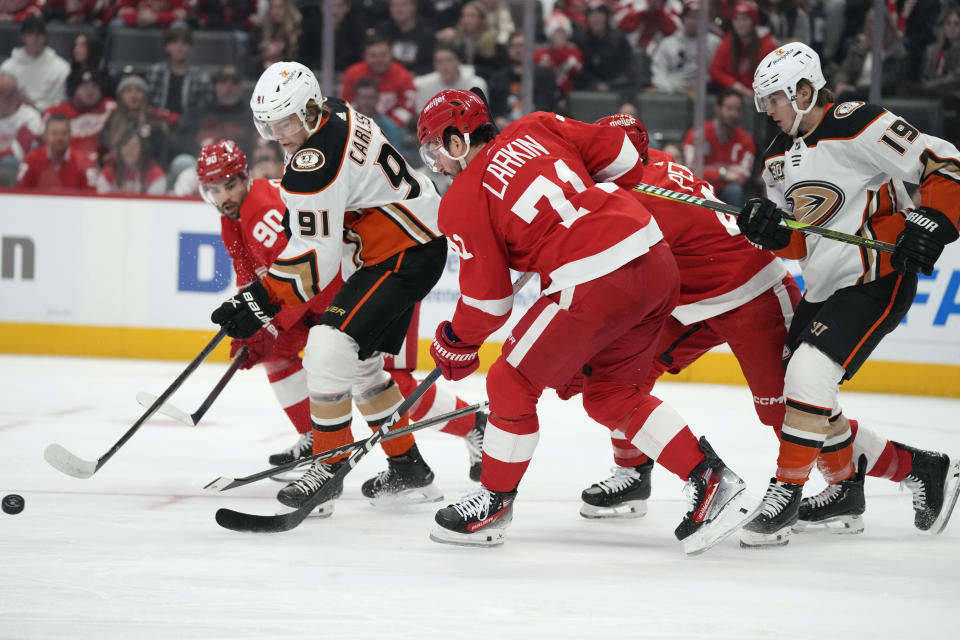 Anaheim Ducks center Leo Carlsson (91) and Detroit Red Wings center Dylan Larkin (71) reach for the puck during the first period of an NHL hockey game, Monday, Dec. 18, 2023, in Detroit. (AP Photo/Carlos Osorio)