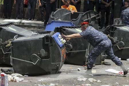 A policeman removes a barricade built with garbage bins by protesters against a hike in electricity prices in Yerevan, Armenia, July 6, 2015. REUTERS/Hayk Baghdasaryan/Photolure