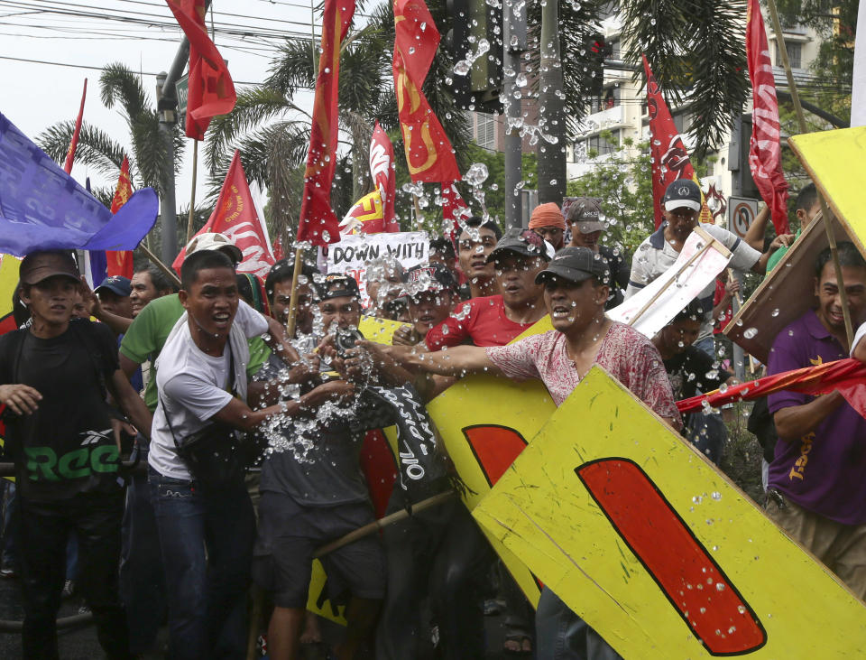 Demonstrators try to shoot a water cannon at police after seizing it from firemen during a clash at U.S. Embassy in Manila, Philippines, Tuesday, Feb. 25, 2014 to protest the forthcoming visit of U.S. President Barack Obama. The protesters were also calling for the pullout of U.S. troops in the country under the Visiting Forces Agreement or VFA. (AP Photo/Bullit Marquez)