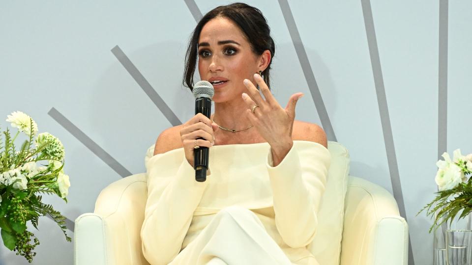 Meghan Markle in a cream suit with a microphone