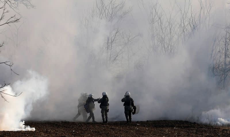 Greek riot police officers stand amid clouds of tear gas near Turkey's Pazarkule border crossing, in Kastanies