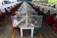 Workers eat their lunch separated by plastic panels as a measure against the spread of the new coronavirus at the Korean-owned firm K.P. Textil in San Miguel Petapa, Guatemala, Friday, July 10, 2020. Employees returned to work after more than a month-long quarantine related to a COVID-19 outbreak involving dozen of workers, implementing new safety protocols to prevent the spread of the virus. (AP Photo/Moises Castillo)