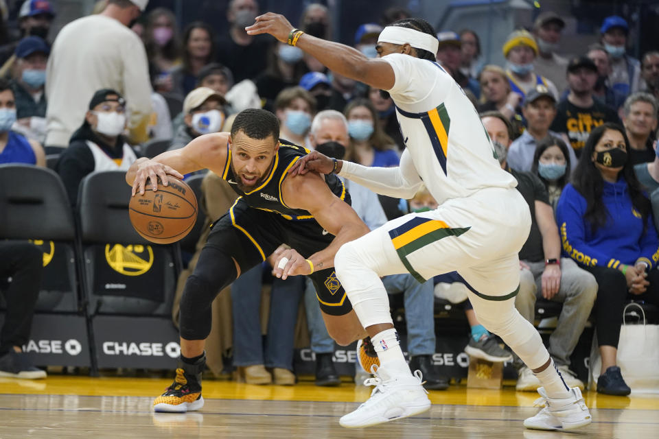 Golden State Warriors guard Stephen Curry, left, drives to the basket against Utah Jazz guard Mike Conley during the first half of an NBA basketball game in San Francisco, Sunday, Jan. 23, 2022. (AP Photo/Jeff Chiu)