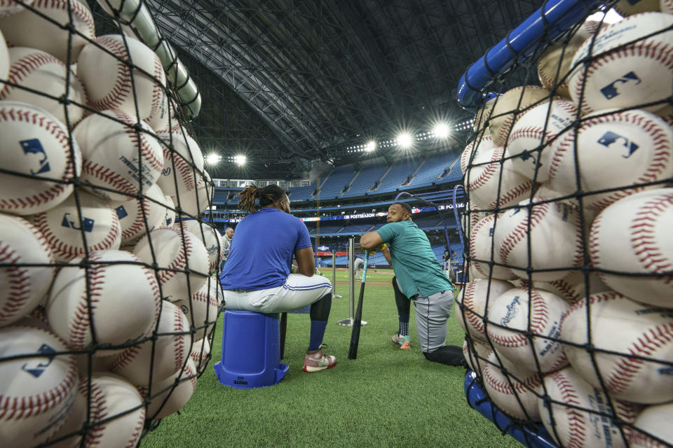 Toronto Blue Jays infielder Vladimir Guerrero Jr. (27), left, and Seattle Mariners designated hitter Carlos Santana (41) speak to each other during practice ahead of their baseball wild-card playoff game in Toronto, Thursday, Oct. 6, 2022. (Alex Lupul/The Canadian Press via AP)