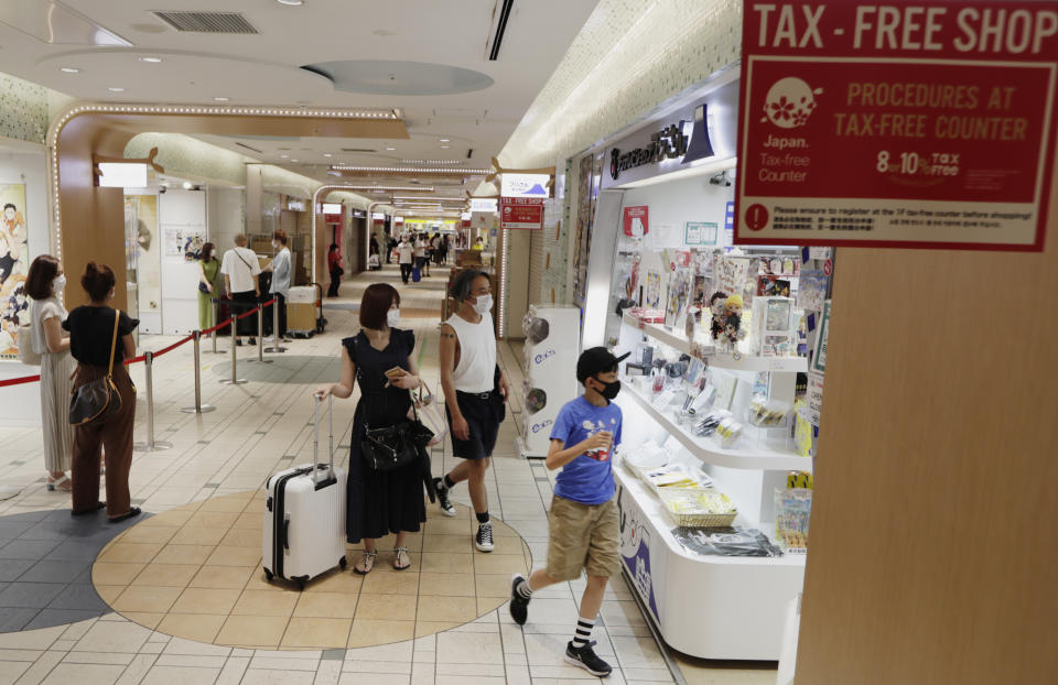 FILE - Shoppers walk into a store at a shopping center in Tokyo on Aug. 17, 2020. The Japanese economy has contracted at an annual rate of 1.2% in the July-September quarter, as consumption declined amid rising prices. (AP Photo/Hiro Komae, File)