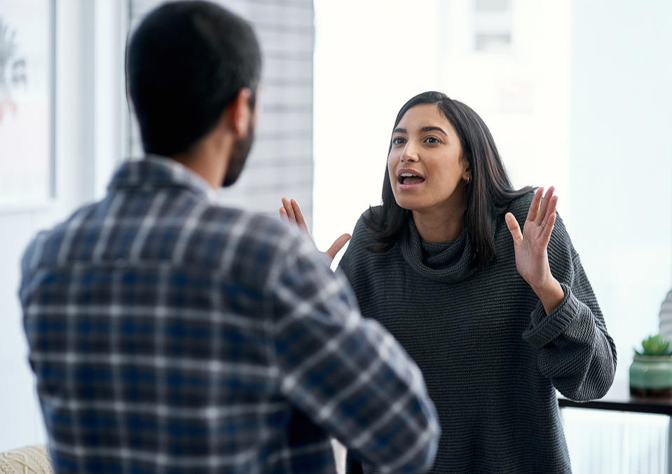 A woman with her hands in the air looking annoyed fighting with a man