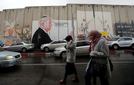 Palestinians walk past a mural depicting U.S. President Donald Trump that is painted on a part of the Israeli barrier, in the West Bank city of Bethlehem December 6, 2017. REUTERS/Mussa Qawasma