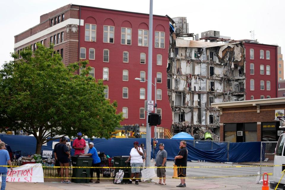 Local residents stand on a sidewalk near a collapsed apartment building, Monday, June 5, 2023, in Davenport, Iowa. The six-story, 80-unit building partially collapsed May 28. (AP Photo/Charlie Neibergall) (Copyright 2023 The Associated Press. All rights reserved.)