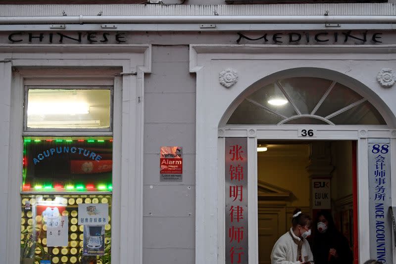 People wear masks as they walk in Chinatown district, in London