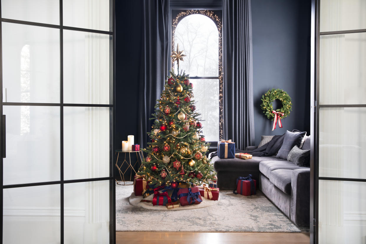  An artificial lit up Christmas tree in a dark blue living room. 