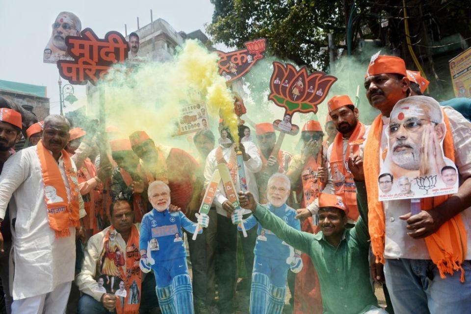 BJP supporters let off smoke flares and are carrying a cutout of Indian Prime Minister Narendra Modi and shouting slogans to celebrate the day of the Lok Sabha election result in Varanasi,