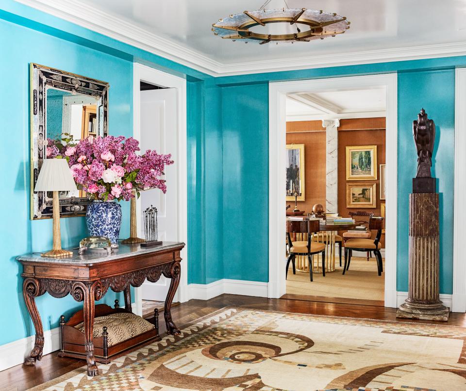 “I painted the front hall electric-blue because it doesn’t have a window and has no light. It’s so much fun to walk into this pop of very strong color.” Light fixture by McEwen Lighting Studio; antique console, mirror, vase, and dog bed from John Rosselli Antiques; 1930s bronze vulture atop 18th-century marble column.