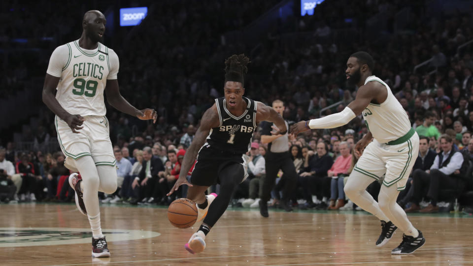 San Antonio Spurs guard Lonnie Walker IV (1) drives between Boston Celtics center Tacko Fall (99) and guard Jaylen Brown (7) during the first half of an NBA basketball game Wednesday, Jan. 8, 2020 in Boston. (AP Photo/Charles Krupa)
