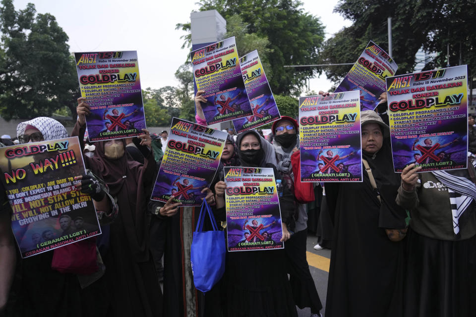Muslim women hold posters during a rally against British band Coldplay ahead of its concert in Jakarta, Indonesia, Wednesday, Nov. 15, 2023. A group of conservative Muslims staged the rally calling for the cancellation of the concert over the band's support for the LGBTQ+ community. (AP Photo/Tatan Syuflana)