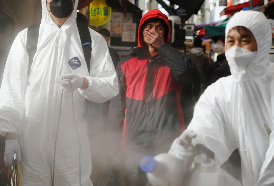 A man reacts as employees from a disinfection service company sanitize a traditional market in Seoul on Feb. 26 | Hong-Ji Kim—REUTERS