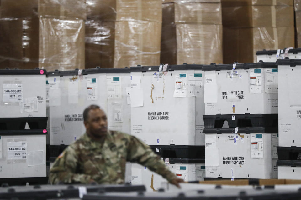 FILE - In this March 23, 2020, file photo, a U.S. National Guard member stands beside crates of medical supplies at the Jacob Javits Center, in New York. The use of National Guard units around the country to help with the response to the coronavirus pandemic is prompting rumors of a national lockdown or even martial law. Guard units are now helping to transport medical supplies, distribute food and even help direct traffic at drive-through testing sites. (AP Photo/John Minchillo, File)