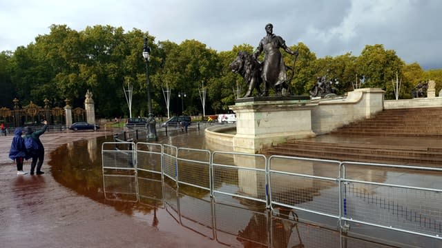 Tourists take a selfie by a flooded Queen Victoria Memorial outside Buckingham Palace