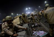 Members of police cross a road divider at a site where farmers have gathered to protest against farm laws at Ghaziabad