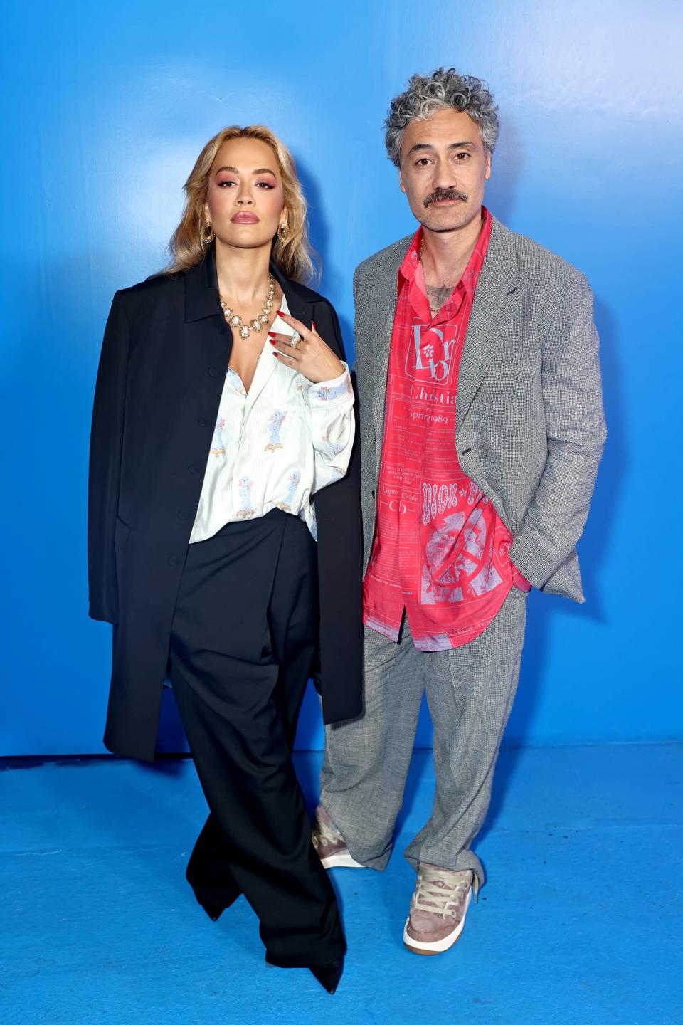 <p>Waititi and Ora initially sparked dating rumors in April 2021 when <a href="http://www.instagram.com/p/CN7nJaBjSZe/?utm_source=ig_web_copy_link" class="link " rel="nofollow noopener" target="_blank" data-ylk="slk:Ora shared a picture of the two embracing">Ora shared a picture of the two embracing</a> on Instagram with the caption, "Good times, memories, random things on my phone and the ones I love." Regarding their relationship, a source told <a href="https://www.thesun.co.uk/tvandshowbiz/14765814/rita-ora-dating-director-taika-waititi-month-sydney/" class="link " rel="nofollow noopener" target="_blank" data-ylk="slk:The Sun">The Sun</a> at the time, "They've been a couple since early March but kept things low key. However, all their friends know about the relationship - they're really into each other." </p> <p>One month after Ora's Instagram post, <a href="https://www.dailymail.co.uk/tvshowbiz/article-9610391/Rita-Ora-Taika-Waititi-pack-PDA-cosy-Tessa-Thompson-night-party.html" class="link " rel="nofollow noopener" target="_blank" data-ylk="slk:The Daily Mail">The Daily Mail</a> reported the pair were not only together but that they were also getting cozy with actress Tessa Thompson. Pictures of the trio showed all three sharing kisses with one another, which, quite frankly, broke the internet. As for Waititi, he didn't think it was all that big a deal. On the pictures and rumors of being a throuple with Thompson, Waititi told <a href="https://www.smh.com.au/culture/movies/in-the-world-of-the-internet-everything-goes-away-pretty-quick-taika-waititi-20210604-p57y1o.html" class="link " rel="nofollow noopener" target="_blank" data-ylk="slk:The Sydney Morning Herald">The Sydney Morning Herald</a>, "Is it that big a deal? No, not really. I was doing nothing wrong. It's fine."</p> <p>Waititi and Ora have stuck together through relentless paparazzi and media buzz, and they're apparently even in the process of planning a <span class="nofilter">wedding</span>. According to <a href="https://www.the-sun.com/entertainment/5512174/rita-ora-secretly-marry-taika-waititi/" class="link " rel="nofollow noopener" target="_blank" data-ylk="slk:The Sun">The Sun</a>, the pair recently got engaged and have plans to marry in an intimate ceremony, then have a showstopping celebration later in the year after their work projects wrap up.</p>