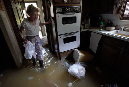 Nancy McBride collects items from her flooded kitchen as she returned to her home for the first time since Harvey floodwaters arrived in Houston, Texas September 1, 2017. REUTERS/Rick Wilking