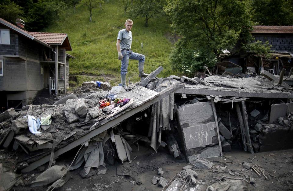 Ervin Cosic poses on top of his flood damaged house in Topcic Polje