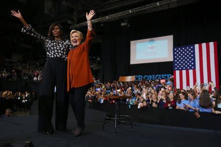 First lady Michelle Obama (L) and U.S. Democratic presidential candidate Hillary Clinton wave after a campaign rally in Winston-Salem, North Carolina, October 27, 2016. REUTERS/Carlos Barria