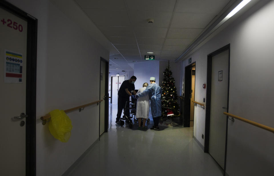 Two Belgian Army medics help a patient to walk who is recovering from COVID-19 at the St. Michiel Hospital in Brussels, Tuesday, Nov. 24, 2020. The Belgian military has been called into several hospitals and care homes to alleviate the stress on healthcare personnel. (AP Photo/Virginia Mayo)