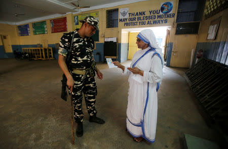 A security personnel checks an identity card of a catholic nun from the Missionaries of Charity as she arrives to cast her vote at a polling station during the final phase of general election in Kolkata, India, May 19, 2019. REUTERS/Rupak De Chowdhuri