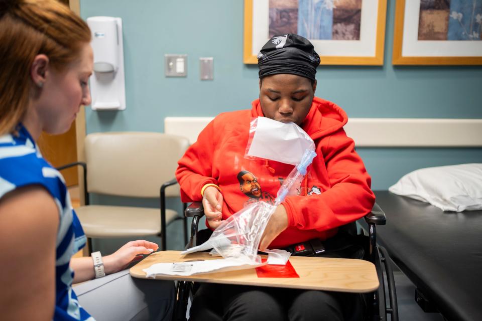 Damarion Allen, 15, uses his mouth to open a catheter bag during occupational therapy at Ohio State Primary Care - Martha Morehouse Outpatient Care. He wants to learn to be more independent. Damarion was paralyzed from the chest down on May 7, 2023, inside the Franklin County Juvenile Intervention Center, and now relies on his four younger siblings and his mother for all of his basic needs.