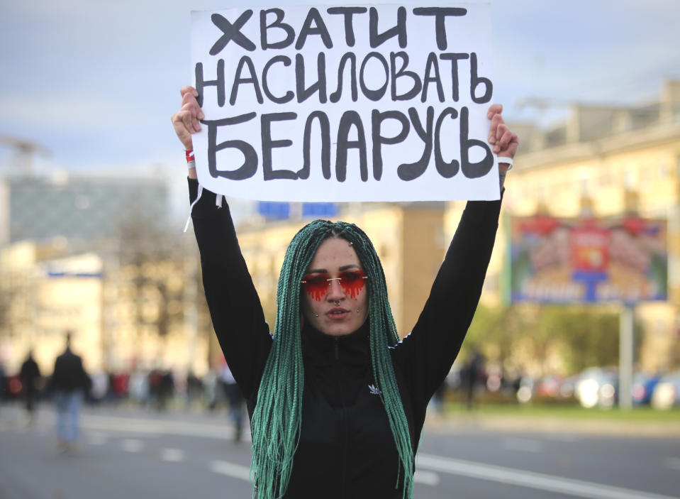 A protester holds a sign reading "Stop raping Belarus" during an opposition rally to protest the official presidential election results in Minsk, Belarus, Sunday, Oct. 18, 2020. Tens of thousands rallied in Minsk once again on Sunday, demanding the resignation of the country's authoritarian leader. Mass weekend protests in the Belarusian capital have continued since Aug. 9, when officials handed President Alexander Lukashenko a landslide victory in an election widely seen as rigged. (AP Photo)