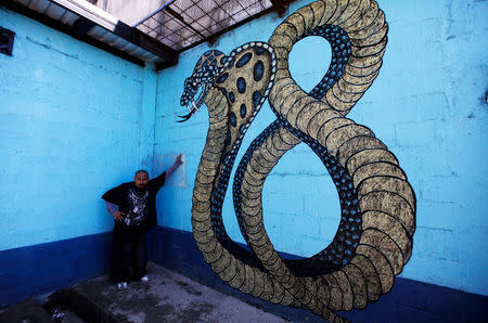 FILE PHOTO: A member of the "Calle 18" street gang stands next to a graffiti of a cobra in the shape of the number 18, at the prison in San Pedro Sula, Honduras May 28, 2013. REUTERS/Jorge Cabrera/File Photo