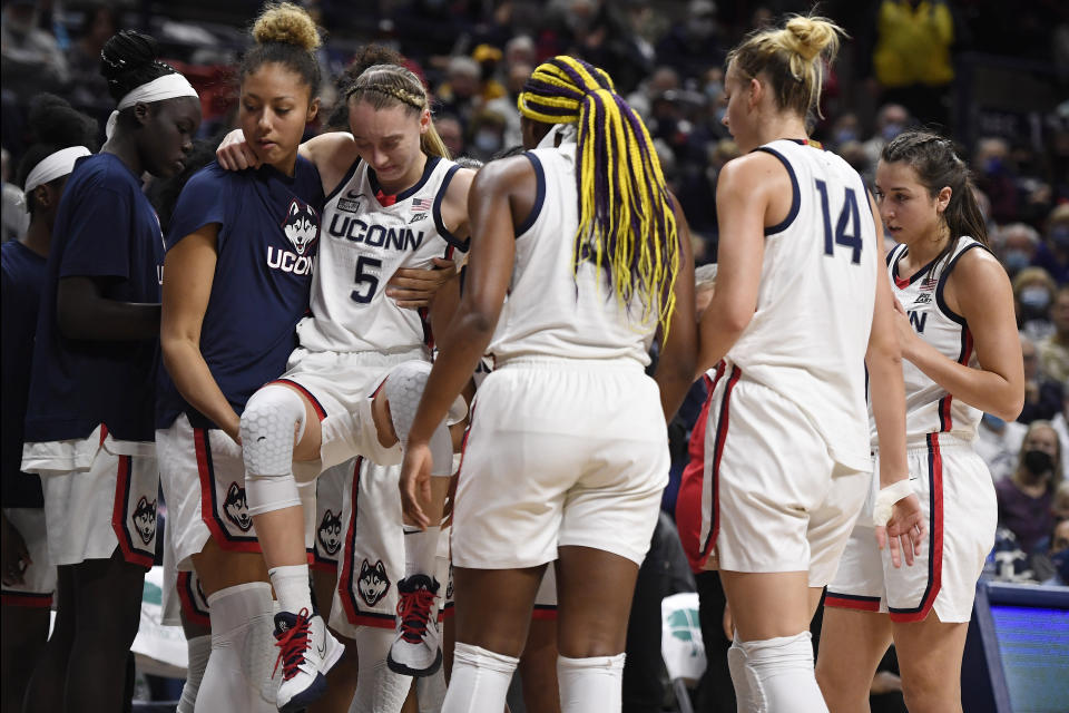 Connecticut's Paige Bueckers (5) is helped off the court by Amari DeBerrym, left, after injuring herself in the second half of an NCAA college basketball game against Notre Dame, Sunday, Dec. 5, 2021, in Storrs, Conn. (AP Photo/Jessica Hill)