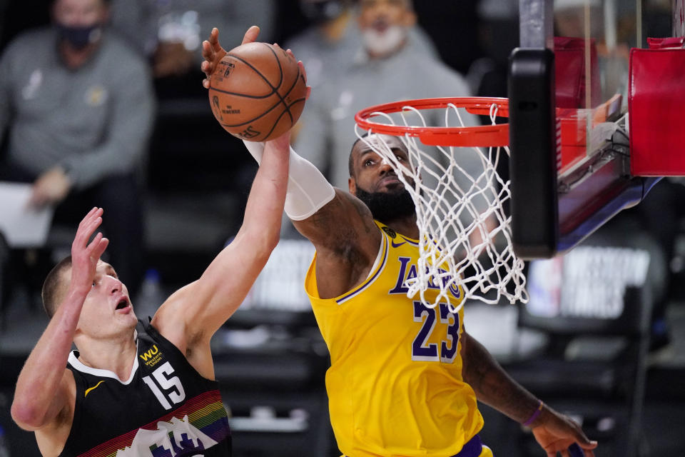 Denver Nuggets' Nikola Jokic (15) and Los Angeles Lakers' LeBron James (23) reach for a rebound during the first half of an NBA conference final playoff basketball game Thursday, Sept. 24, 2020, in Lake Buena Vista, Fla. (AP Photo/Mark J. Terrill)