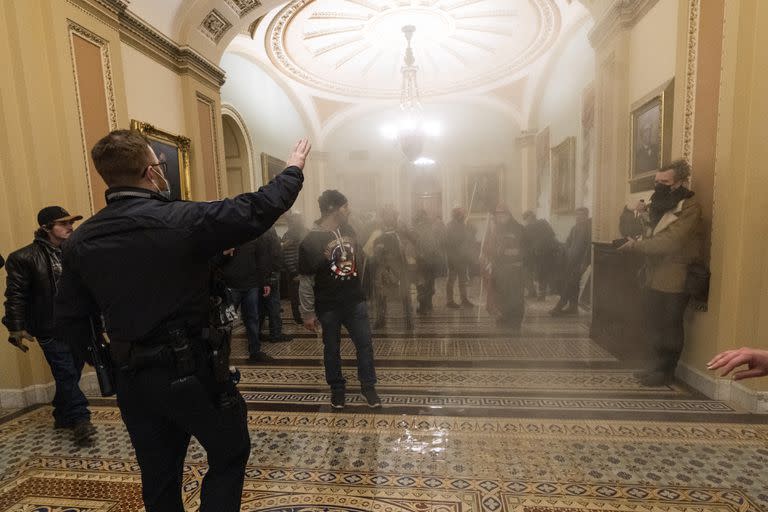 Una nube de humo llena el pasillo frente al Senado durante una confrontación entre policías del Capitolio y simpatizantes del presidente Trump el 6 de enero